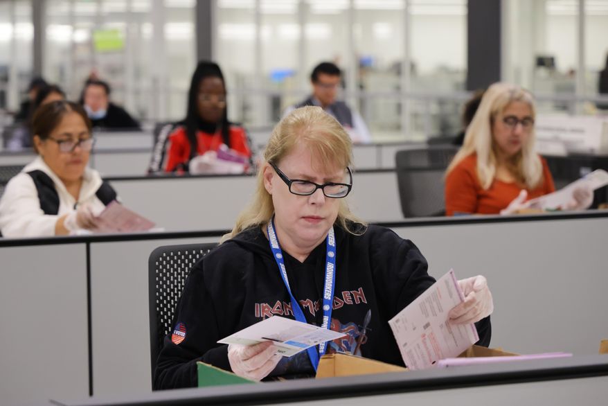 A worker examines ballots at the L.A. County Ballot Processing Center on Tuesday, Nov. 4, 2025, in City of Industry, Calif. (AP Photo/Ethan Swope)