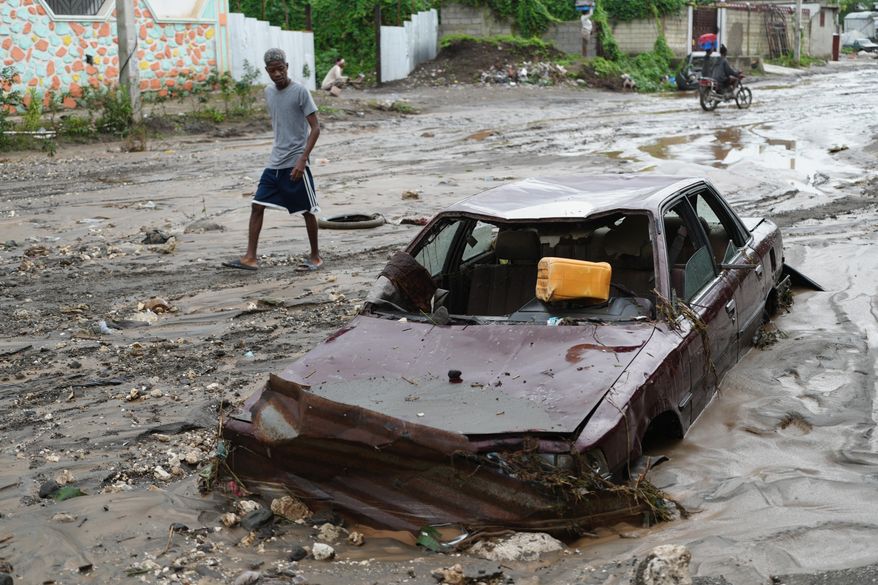 A pedestrian looks a at flooded car in the aftermath of Hurricane Melissa in Petit-Goave, Haiti, Thursday, Oct. 30, 2025. (AP Photo/Odelyn Joseph),