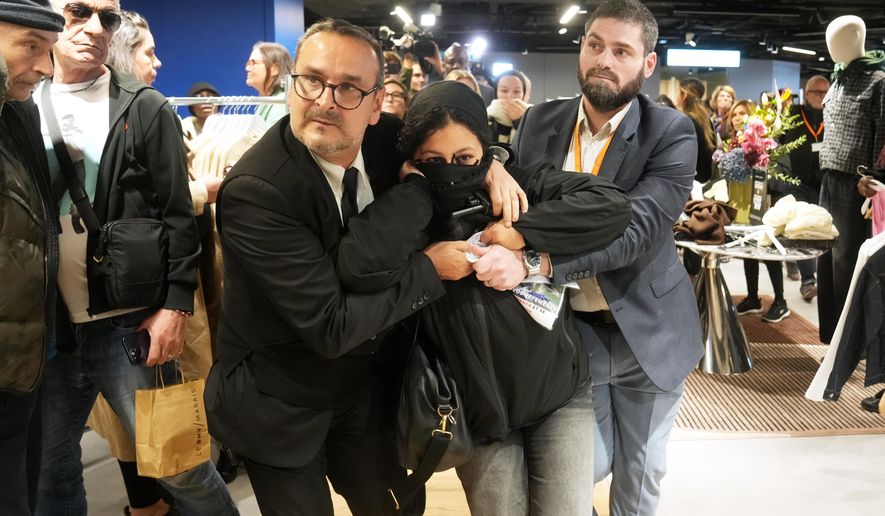 A protester is being evacuated from the BHV department store as fast fashion Shein opens its first physical store, Wednesday, Nov. 5, 2025 in Paris. (AP Photo/Thibault Camus)