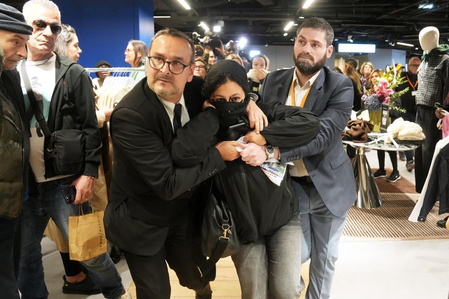 A protester is being evacuated from the BHV department store as fast fashion Shein opens its first physical store, Wednesday, Nov. 5, 2025 in Paris. (AP Photo/Thibault Camus)