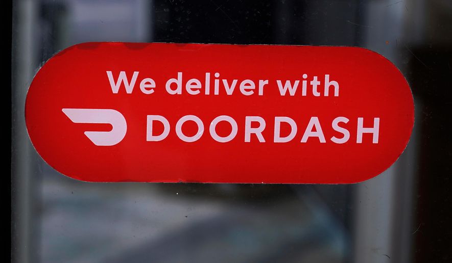 A DoorDash sign is posted on the door of a Dunkin' Donuts franchise, Feb. 27, 2023, in Methuen, Mass. (AP Photo/Charles Krupa, File)