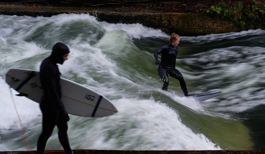 FILE - Surfer ride on an artificial wave in the river 'Eisbach' at the 'Englischer Garten' (English Garden) downtown in Munich, Germany, Monday, Oct. 6, 2025. (AP Photo/Matthias Schrader, File)