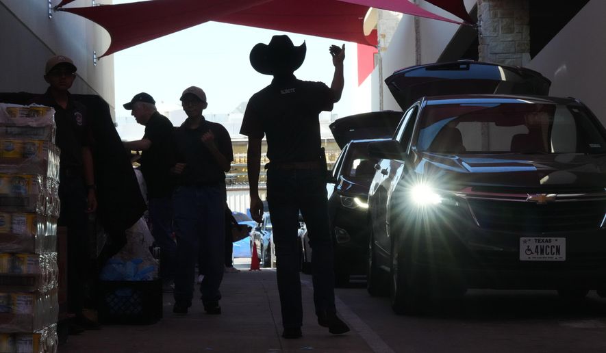 Aidan Tavor, center, directs traffic as volunteers help load vehicles during a food distribution at the San Antonio Food Bank for SNAP recipients and other households affected by the federal shutdown, Thursday, Nov. 6, 2025, in San Antonio. (AP Photo/Eric Gay)