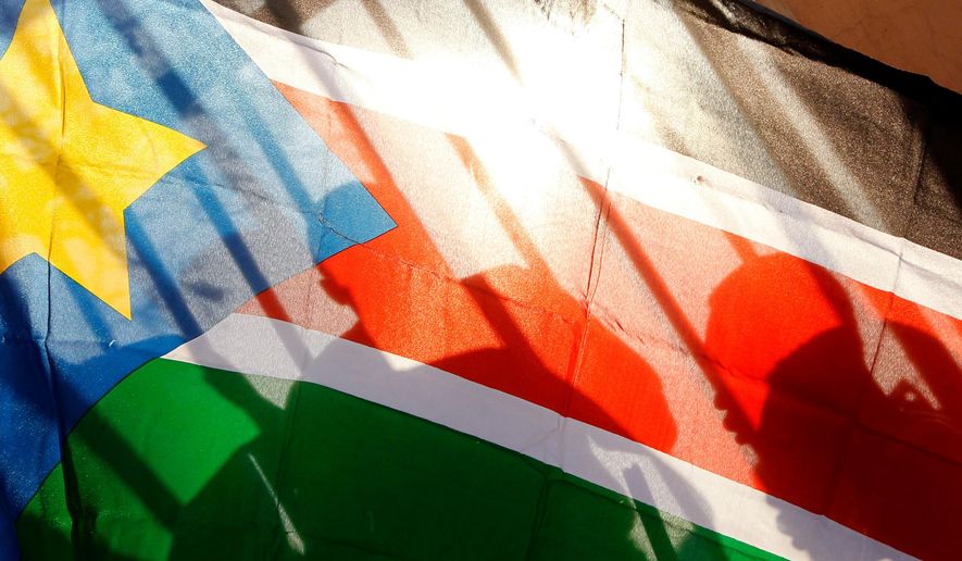 FILE - The silhouettes of South Sudanese people are seen through a South Sudanese flag as they line up to cast their votes in Juba, South Sudan, Jan. 9, 2011. (AP Photo/Jerome Delay, File)