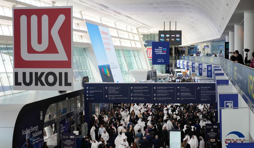 Logo of Russian oil company Lukoil hangs from the ceiling as visitors and delegates leave the hall after the inaugural session of annual Abu Dhabi International Petroleum Exhibition & Conference (ADIPEC) in Abu Dhabi, United Arab Emirates, Monday, Nov. 3, 2025. (AP Photo/Altaf Qadri)