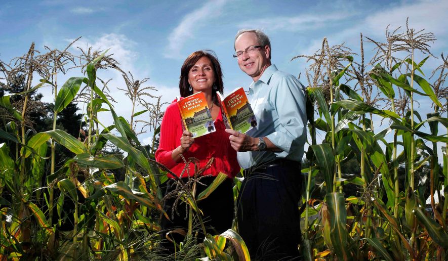 Farmers' Almanac editor Sondra Duncan and publisher Peter Geiger pose in a corn field with the 2012 edition of the almanac, Aug. 24, 2011, in Auburn, Maine. (AP Photo/Robert F. Bukaty, File)