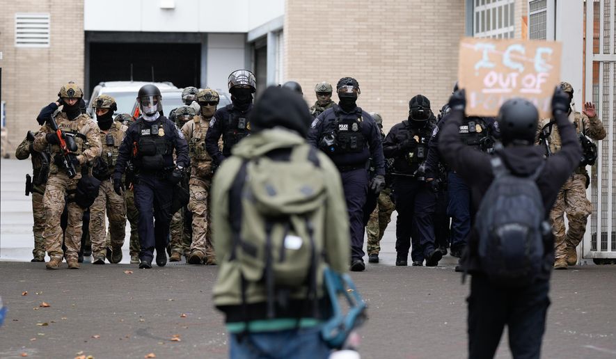 People protest outside a U.S. Immigration and Customs Enforcement facility as law enforcement officers walk out of the gates to guard vehicles leaving the facility on Oct. 11, 2025, in Portland, Ore. (AP Photo/Jenny Kane, File)