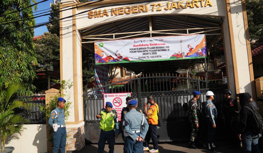 Police officers and military personnel stand guard at the gate of a school where explosions reportedly occurred, in Jakarta, Indonesia, Friday, Nov. 7, 2025. (AP Photo/Dita Alangkara)
