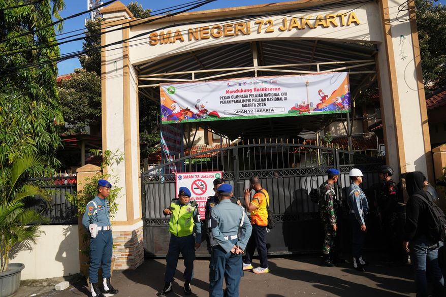 Police officers and military personnel stand guard at the gate of a school where explosions reportedly occurred, in Jakarta, Indonesia, Friday, Nov. 7, 2025. (AP Photo/Dita Alangkara)