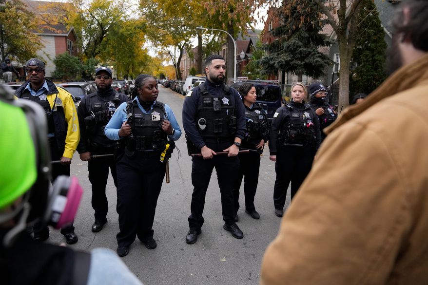 Chicago police officers block a street as people protest the actions of federal immigration agents in Little Village, Saturday, Nov. 8, 2025, in Chicago. (AP Photo/Erin Hooley)