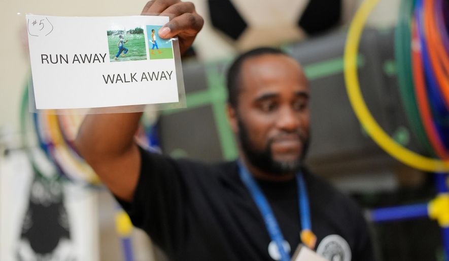 Health and physical education teacher Ronald Anderson holds instructions for students when they encounter a firearm during a gun safety lesson at Berclari Elementary School, Monday, Oct. 27, 2025, in Memphis, Tenn. (AP Photo/George Walker IV)