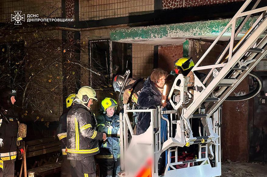 In this photo provided by the Ukrainian Emergency Service, firefighters evacuate a resident following a Russian rocket attack that hit a multi-storey apartment building in Dnipro, Ukraine, Saturday, Nov. 8, 2025. (Ukrainian Emergency Service via AP)