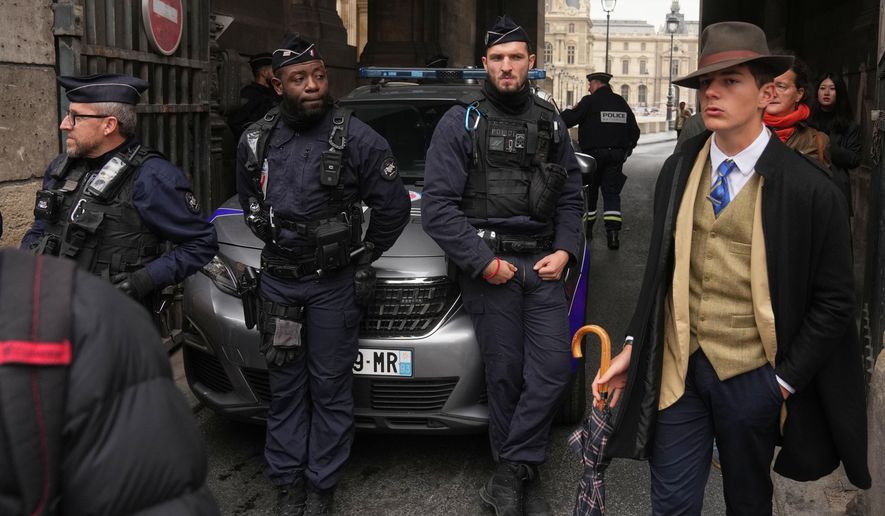 FILE - Pedro Elias Garzon Delvaux, right, walks past as police officers block an entrance to the Louvre after thieves carried out a daylight raid on French crown jewels, in Paris, Oct. 19, 2025. (AP Photo/Thibault Camus, File)