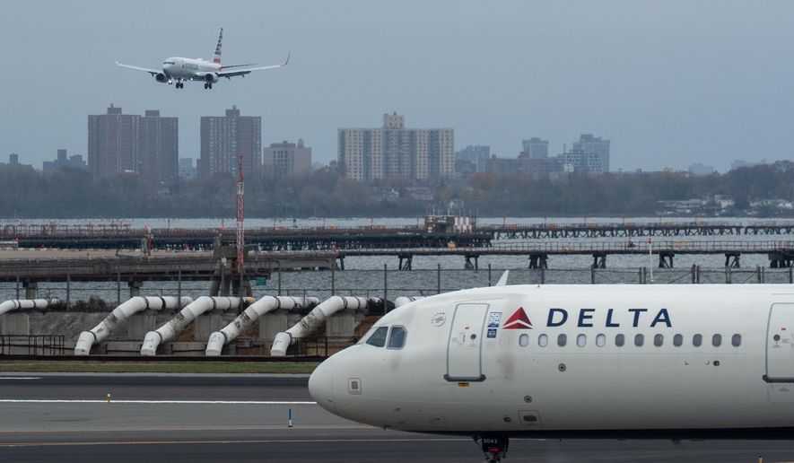 An American Airlines flight lands as a Delta Air Lines plane taxis at LaGuardia Airport (LGA) in the Queens borough of New York, Sunday, Nov. 9, 2025. (AP Photo/Adam Gray)