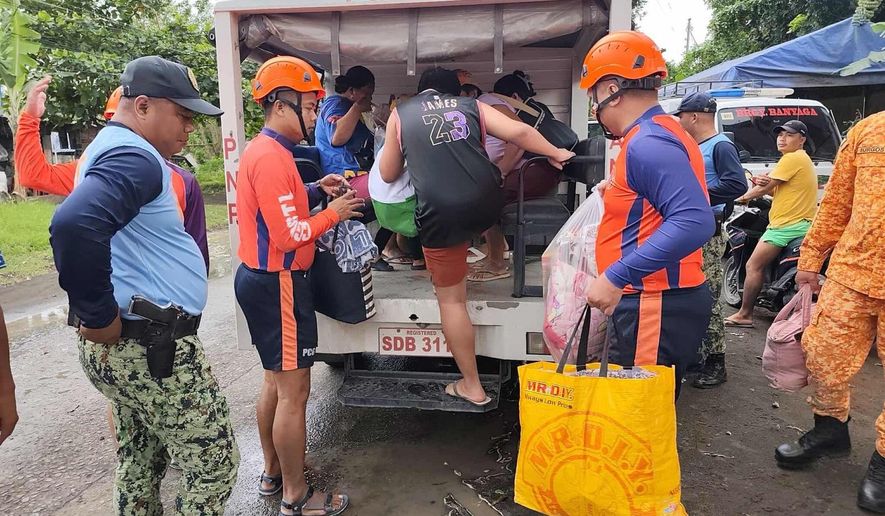 In this photo provided by the Philippine Coast Guard, rescuers evacuate people to safer grounds in Quezon province, eastern Philippines as Typhoon Fung-wong enters the country on Sunday Nov. 9 2025. (Philippine Coast Guard via AP)