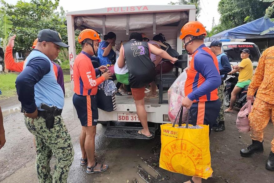 In this photo provided by the Philippine Coast Guard, rescuers evacuate people to safer grounds in Quezon province, eastern Philippines as Typhoon Fung-wong enters the country on Sunday Nov. 9 2025. (Philippine Coast Guard via AP)