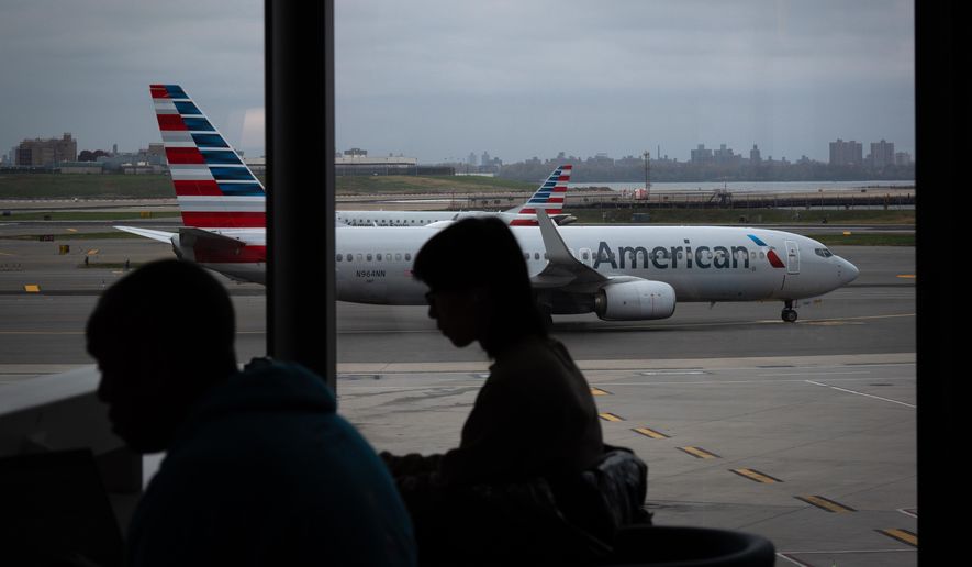 People wait for flights as an American Airlines plane taxis at LaGuardia Airport (LGA), in the Queens borough of New York, Sunday, Nov. 9, 2025. (AP Photo/Adam Gray)