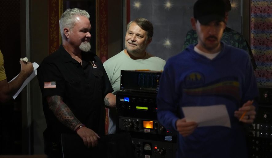 Army veterans David Booth, left, and Clay Jensen, center, watch as musicians and sound technicians prepare to record a song based on their military experiences on Wednesday, Sept. 9, 2025, in Nashville, Tenn. (AP Photo/Mark Humphrey)