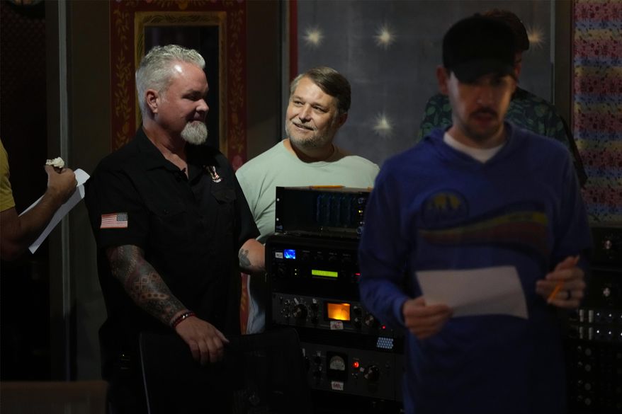 Army veterans David Booth, left, and Clay Jensen, center, watch as musicians and sound technicians prepare to record a song based on their military experiences on Wednesday, Sept. 9, 2025, in Nashville, Tenn. (AP Photo/Mark Humphrey)