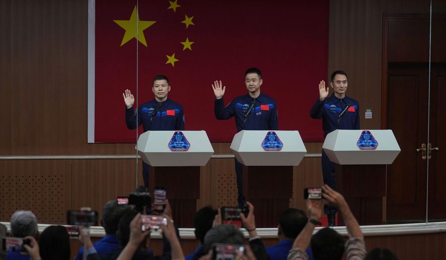 Journalists film Chinese astronauts for the upcoming Shenzhou 20 mission, from left, Wang Jie, Capt. Chen Dong and Chen Zhongrui wave at the Jiuquan Satellite Launch Center in northwest China, Wednesday, April 23, 2025. (AP Photo/Andy Wong, File)