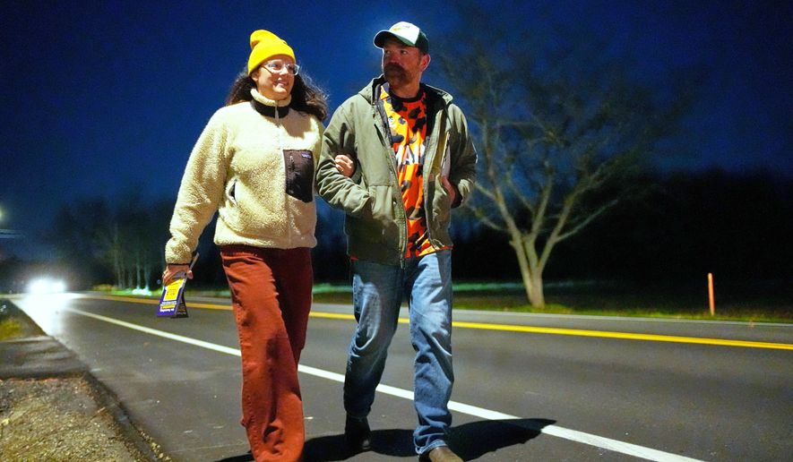 Graham Platner, Democratic candidate for U.S. Senate, and his wife, Amy Gertner, walk on the shoulder of the road while canvassing for a citizen's initiate on Election Day, Tuesday, Nov. 4, 2025, in Ellsworth, Maine. (AP Photo/Robert F. Bukaty)