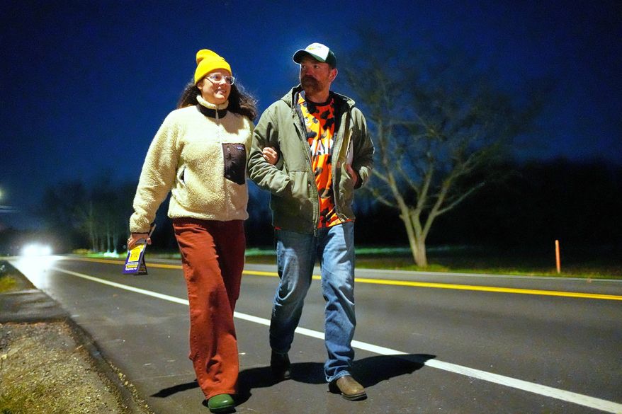 Graham Platner, Democratic candidate for U.S. Senate, and his wife, Amy Gertner, walk on the shoulder of the road while canvassing for a citizen's initiate on Election Day, Tuesday, Nov. 4, 2025, in Ellsworth, Maine. (AP Photo/Robert F. Bukaty)