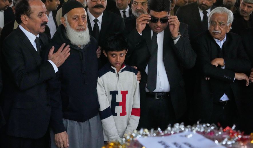 Mourners comfort Yahya Zubair, son of lawyer Zubair Aslam Ghumman, who was killed in Tuesday's suicide bombing outside the gates of a district court, during a funeral prayer, in Islamabad, Pakistan, Wednesday, Nov. 12, 2025. (AP Photo/Anjum Naveed)
