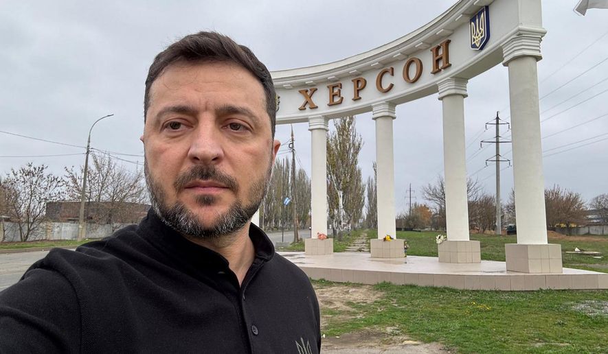 In this photo provided by the Ukrainian Presidential Press Office, Ukrainian President Volodymyr Zelenskyy stands at the sign reading "Kherson" at the approaches to the front line city of Kherson, Southern Ukraine, Tuesday, Nov. 11, 2025. (Ukrainian Presidential Press Office via AP)