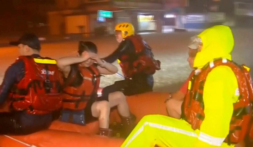 In this image taken from video by Taiwan's EBC, rescuers evacuate stranded people using an inflatable boat in Yilan County in northeastern Taiwan on Tuesday, Nov. 11. 2025. (EBC via AP )