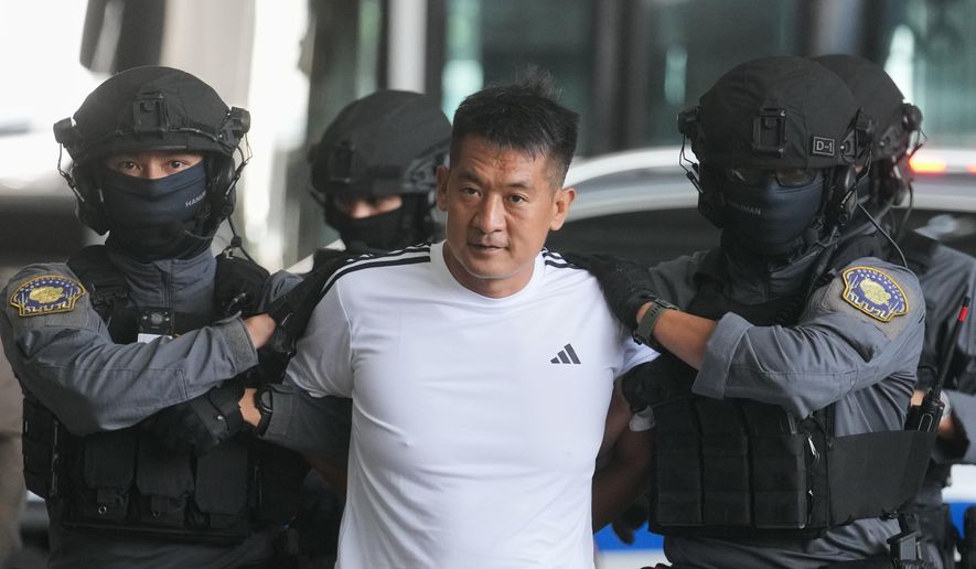 She Zhijiang, an alleged transnational crime kingpin accused by Beijing of having run illegal online gambling operations, is escorted by police at Suvarnabhumi International Airport in Thailand's Samut Prakarn province ahead of being extradited to China, Wednesday, Nov. 12, 2025. (AP Photo/Sakchai Lalit)