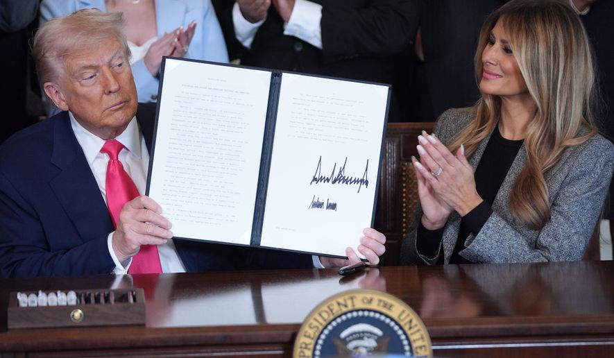 President Donald Trump displays an signed executive order as first lady Melania Trump watches during an event on foster care in the East Room of the at the White House, Thursday, Nov. 13, 2025, in Washington. (AP Photo/Evan Vucci)