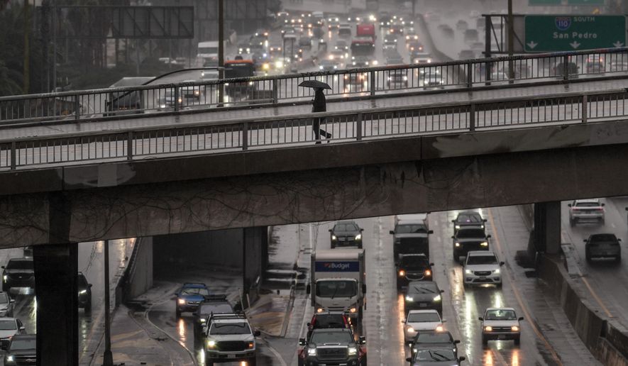 A pedestrian with an umbrella walks on a bridge over the rain-soaked 110 Freeway in Los Angeles Friday, Nov. 14, 2025. (AP Photo/Jae C. Hong)
