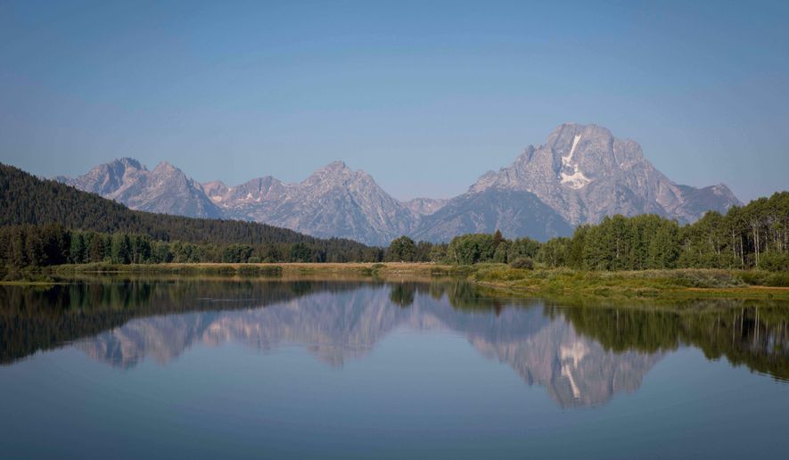 The Teton mountains reflect on Oxbow Bend in Grand Teton National Park in Moran, Wyo., on Friday, Aug. 22, 2025. (AP Photo/Amber Baesler, File)