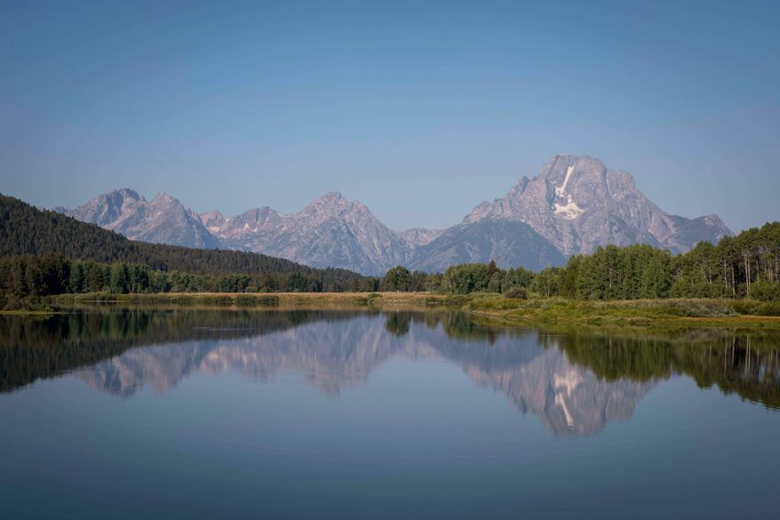 The Teton mountains reflect on Oxbow Bend in Grand Teton National Park in Moran, Wyo., on Friday, Aug. 22, 2025. (AP Photo/Amber Baesler, File)