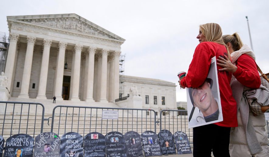 Jen Trejo holds a photo of her son Christopher as she is comforted outside the Supreme Court Dec. 4, 2023, in Washington. (AP Photo/Stephanie Scarbrough, File)