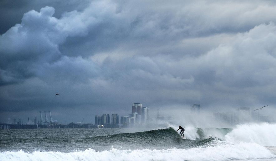 A surfer rides a wave as clouds gather above Bolsa Chica State Beach in Orange County, Calif., on Saturday, Nov. 15, 2025. (AP Photo/Noah Berger)