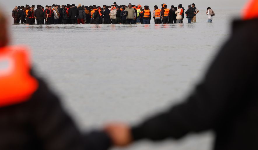Migrants push a small boat in an attempt to reach Britain, Thursday, Nov. 6, 2025 in Gravelines, northern France. (AP Photo/Jean-Francois Badias)