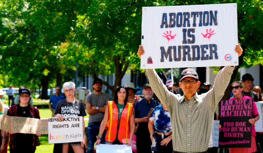 FILE - A man supporting restrictions on abortion holds a sign as abortion-rights supporters hold signs behind him outside the South Carolina Statehouse on Thursday, July 7, 2022, in Columbia, S.C. (AP Photo/Meg Kinnard, File)