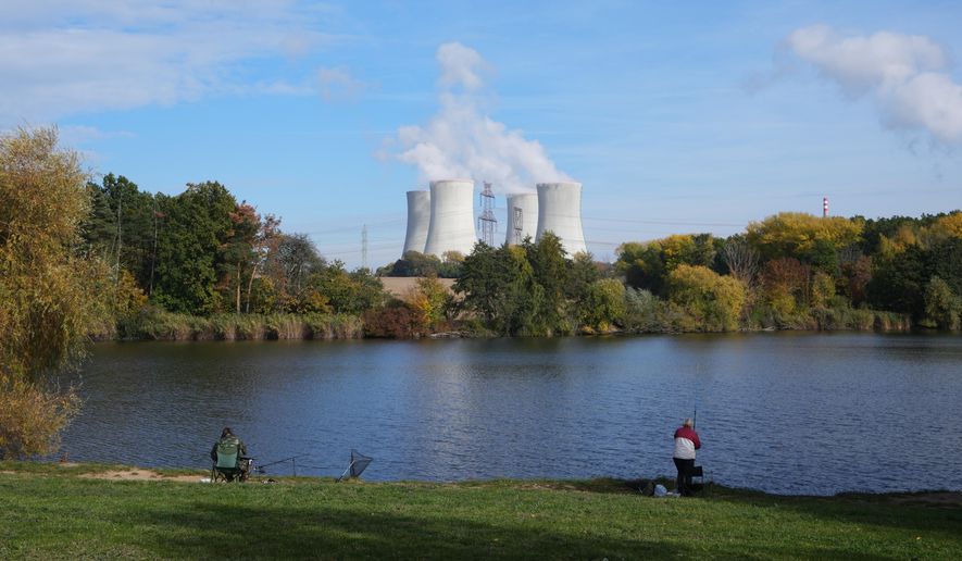 People fish near the towering Dukovany nuclear power plant, background, in Dukovany, Czech Republic, Oct. 21, 2025. (AP Photo/Petr David Josek)
