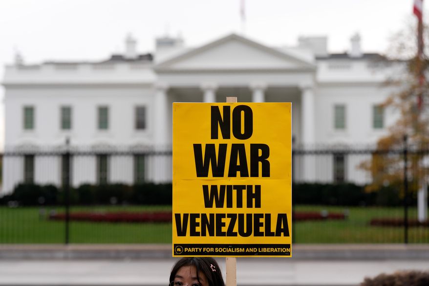 A demonstrator holds a sign while protesting outside of the White House in Washington, Saturday, Nov. 15, 2025. (AP Photo/Jose Luis Magana)