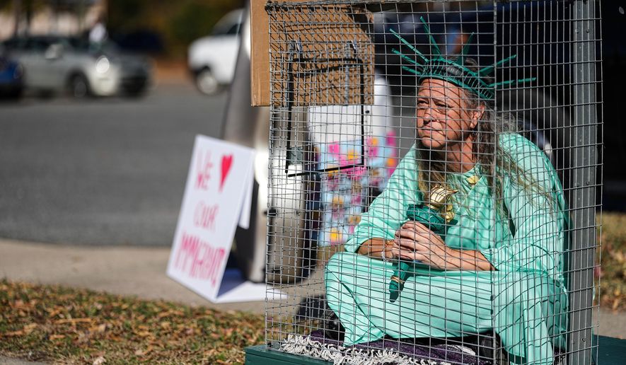 Shana Blake sits in a cage dressed as the Statue of Liberty to protest federal law enforcement presence in Charlotte, N.C. Monday, Nov. 17, 2025. (AP Photo/Matt Kelley)