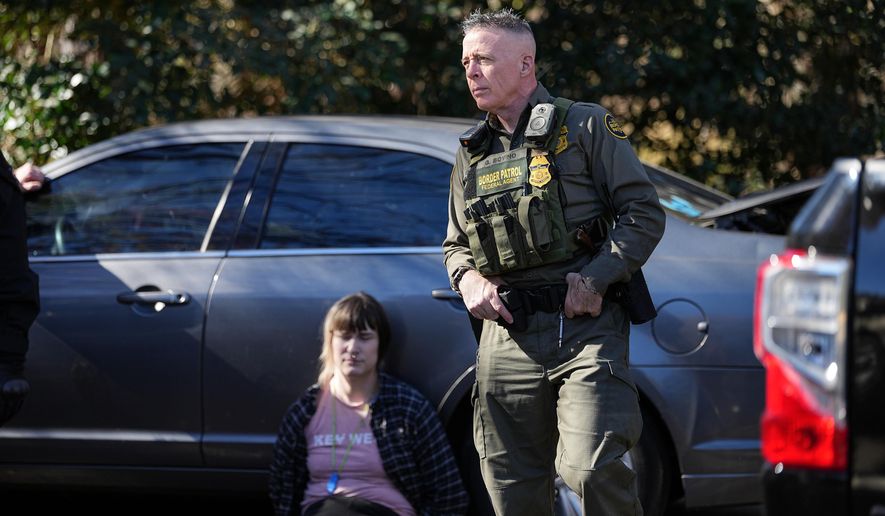 U.S. Border Patrol Commander at large Gregory Bovino, right, looks on as a detainee sits by a car, Monday, Nov. 17, 2025, in Charlotte, N.C. (AP Photo/Matt Kelley)