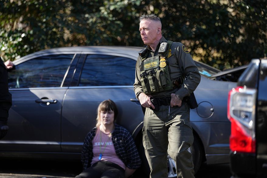 U.S. Border Patrol Commander at large Gregory Bovino, right, looks on as a detainee sits by a car, Monday, Nov. 17, 2025, in Charlotte, N.C. (AP Photo/Matt Kelley)