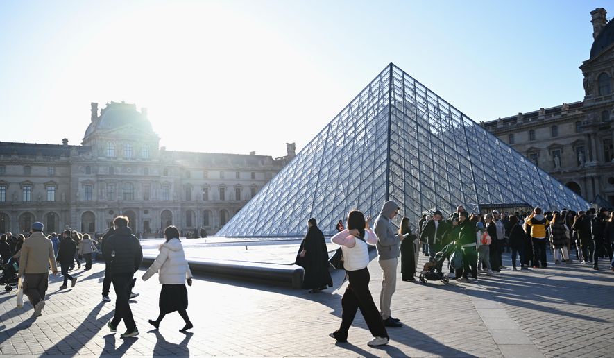 People wait for the opening of the Louvre museum, Thursday, Oct. 30, 2025 in Paris. (AP Photo/Emma Da Silva)