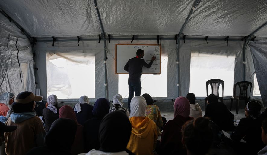 Palestinian students attend class inside a tent set up on the beach in Khan Younis, Gaza Strip, Wednesday, Nov. 12, 2025. (AP Photo/Abdel Kareem Hana)