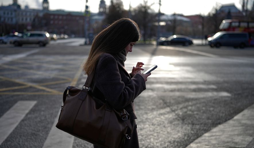 A woman looks at her smartphone in central Moscow, Russia, Thursday, Nov. 20, 2025. (AP Photo/Alexander Zemlianichenko)