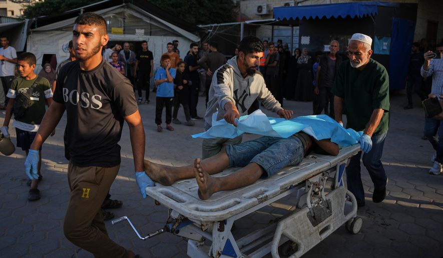 Palestinians wheel the body of a man killed in Israeli strikes on the Gaza Strip to the morgue at Al-Aqsa Hospital in Deir al-Balah, Saturday, Nov. 22, 2025. (AP Photo/Abdel Kareem Hana)