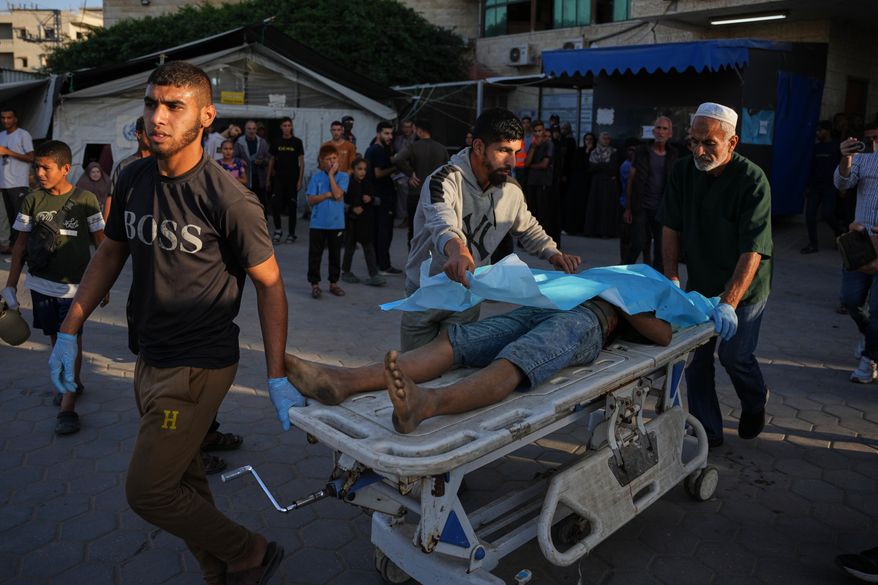 Palestinians wheel the body of a man killed in Israeli strikes on the Gaza Strip to the morgue at Al-Aqsa Hospital in Deir al-Balah, Saturday, Nov. 22, 2025. (AP Photo/Abdel Kareem Hana)