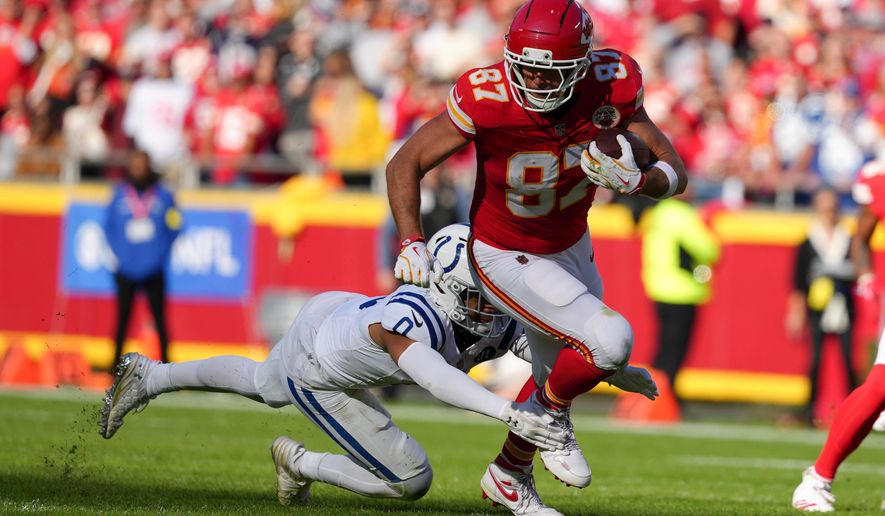 Kansas City Chiefs tight end Travis Kelce (87) is tackled by Indianapolis Colts safety Camryn Bynum (0) during the first half of an NFL football game Sunday, Nov. 23, 2025, in Kansas City, Mo. (AP Photo/Ed Zurga)