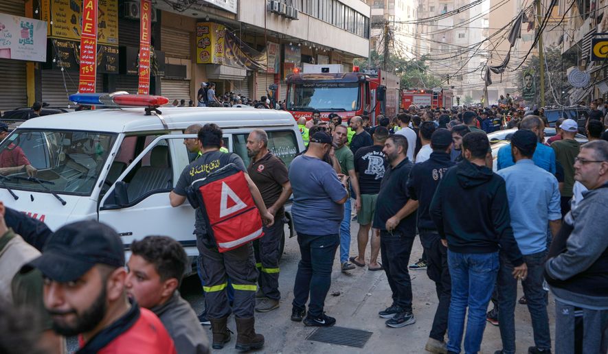 People and Civil Defence workers gather at the site where an Israeli airstrike hit an apartment building on Dahiyeh in the southern suburb of Beirut, Sunday Nov. 23, 2025. (AP Photo/Bilal Hussein)
